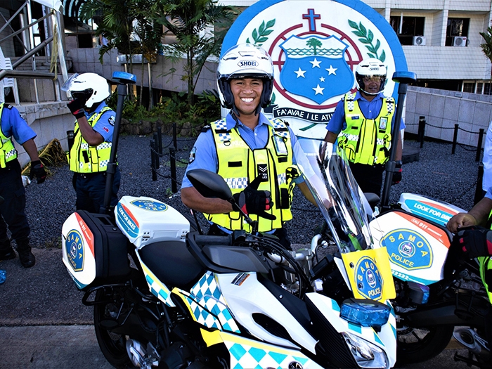 uniformed police officer standing next to a motorbike