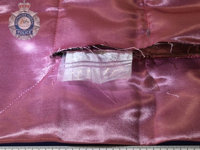 A plastic sleeve filled with a white powdery substance is poking out of a pink silk cloth.