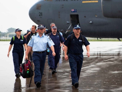 A group of Australian police officers walking across an airport tarmac away from an aeroplane
