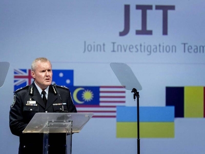 A senior police officer, Assistant Commissioner Peter Crozier, giving a speech on stage in front a ‘Joint Investigation Team’ banner